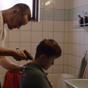 A man is shaving a boy