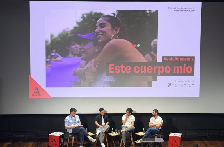 Los protagonistas de la película "Este cuerpo mío" en un pase en el cine, con el póster de la película detrás.